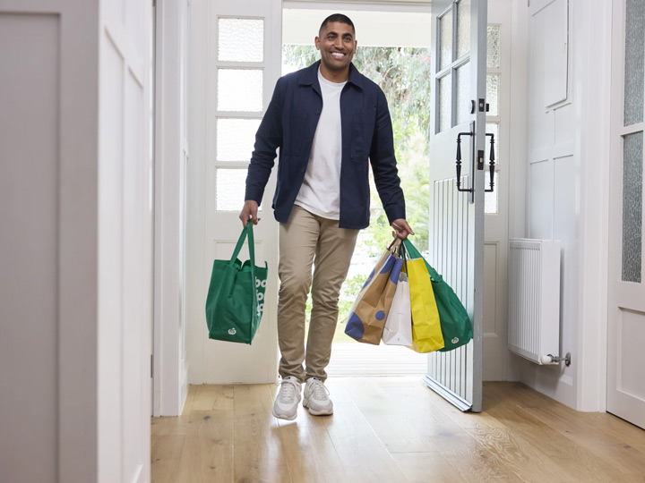 Man carrying shopping bags into his house