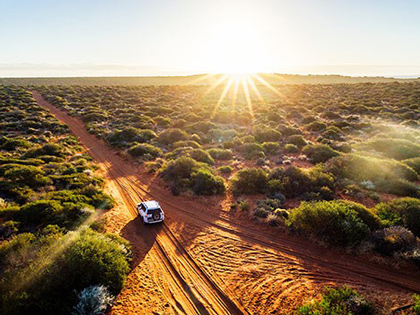 A white 4WD driving in the Australian outback.