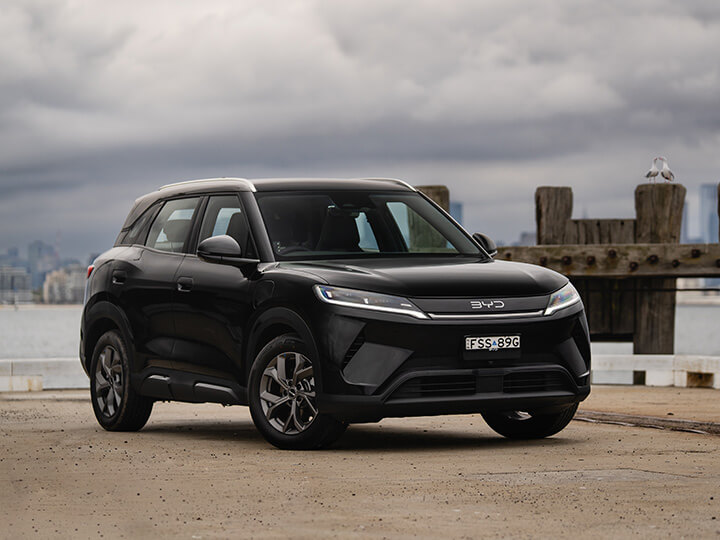 Black BYD Atto parked near the waterfront with a cloudy skyline.