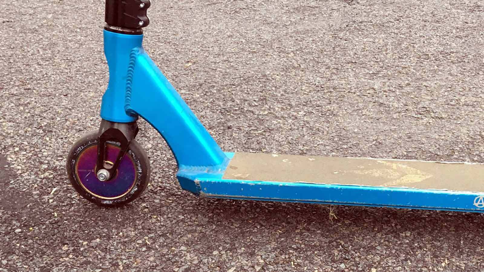 Blue scooter parked on pavement.