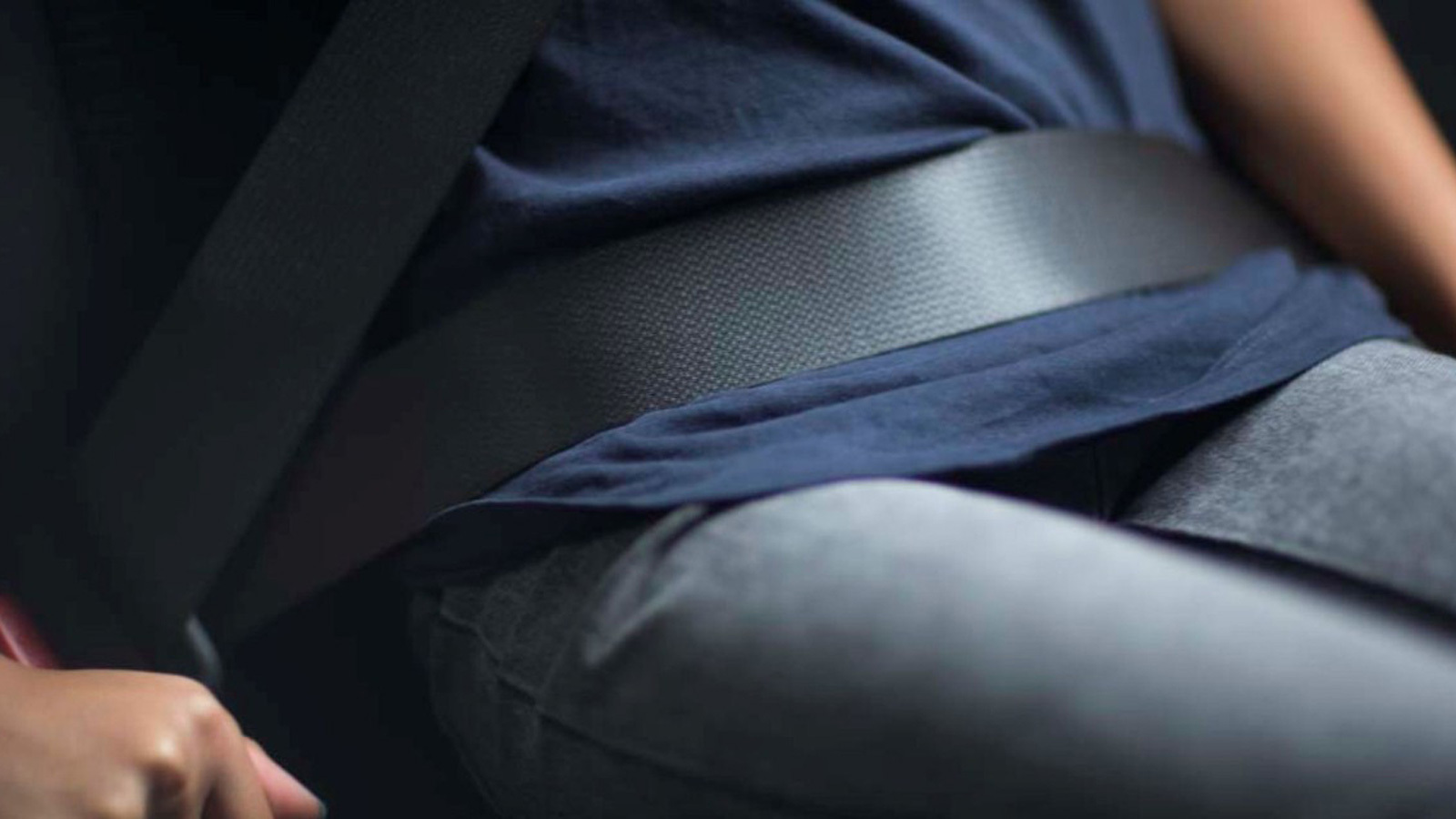 Person sitting in a car and wearing a seatbelt.