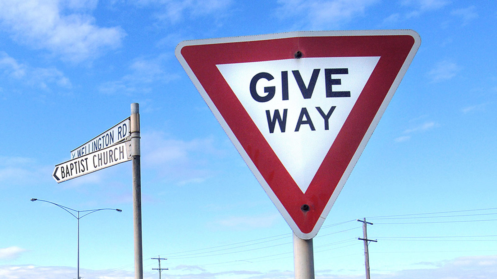 Give way sign in front of a street sign.