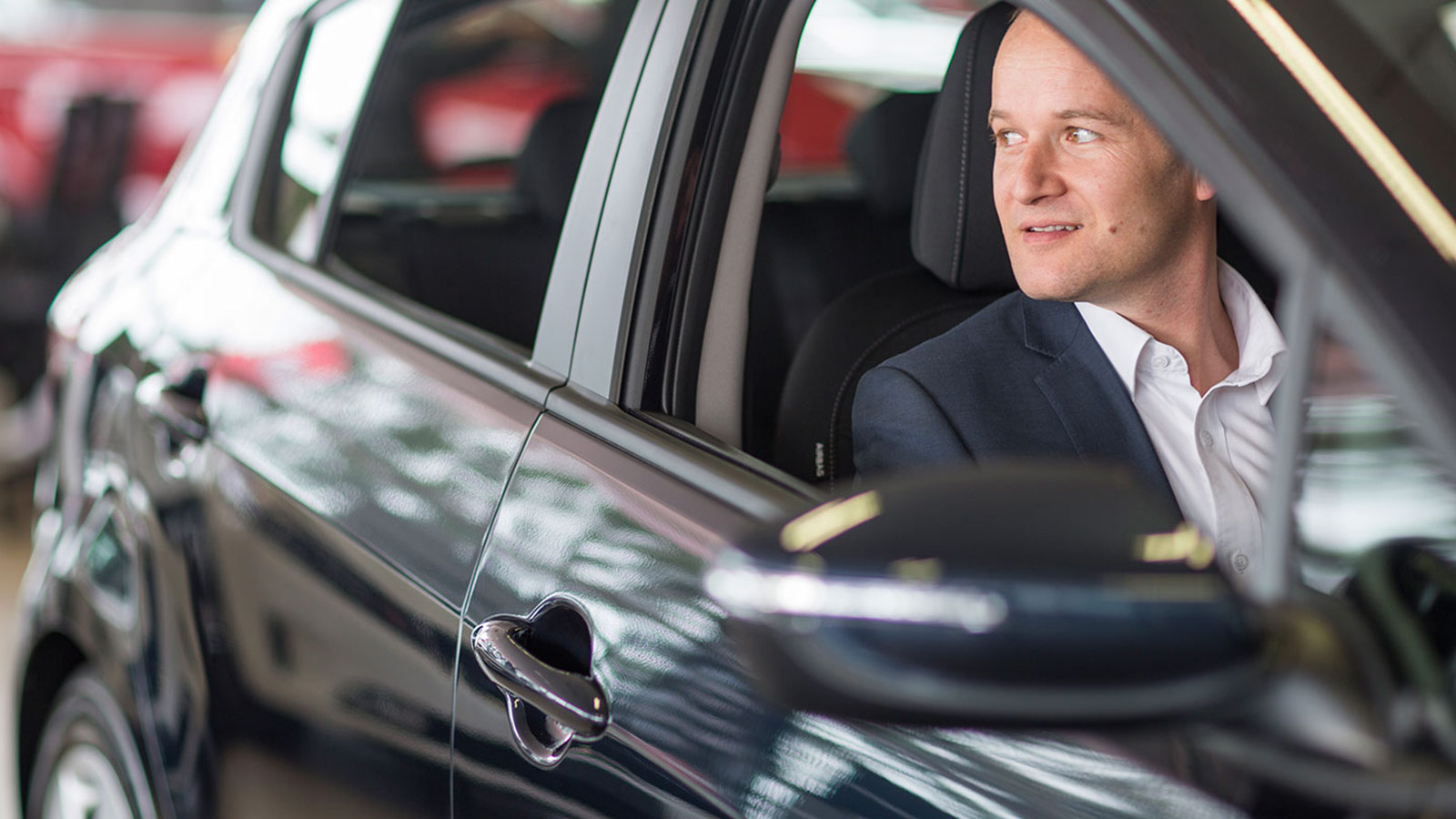 Person in a car dealership, sitting inside a Kia car.