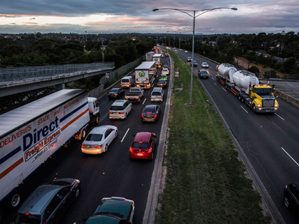 Busy highway at dusk with cars and trucks.