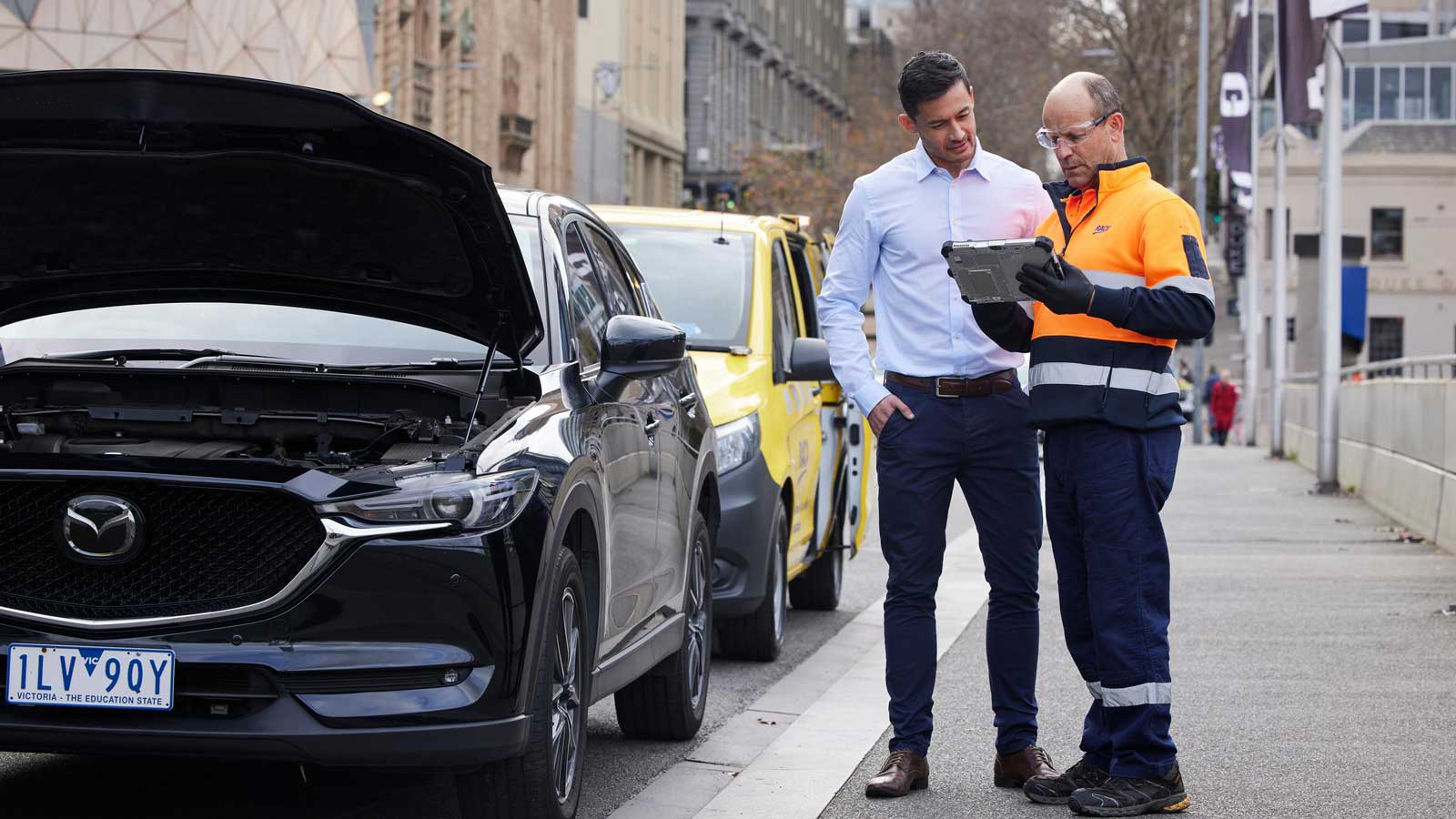 RACV roadside assistance technician speaking with a customer in Melbourne city.