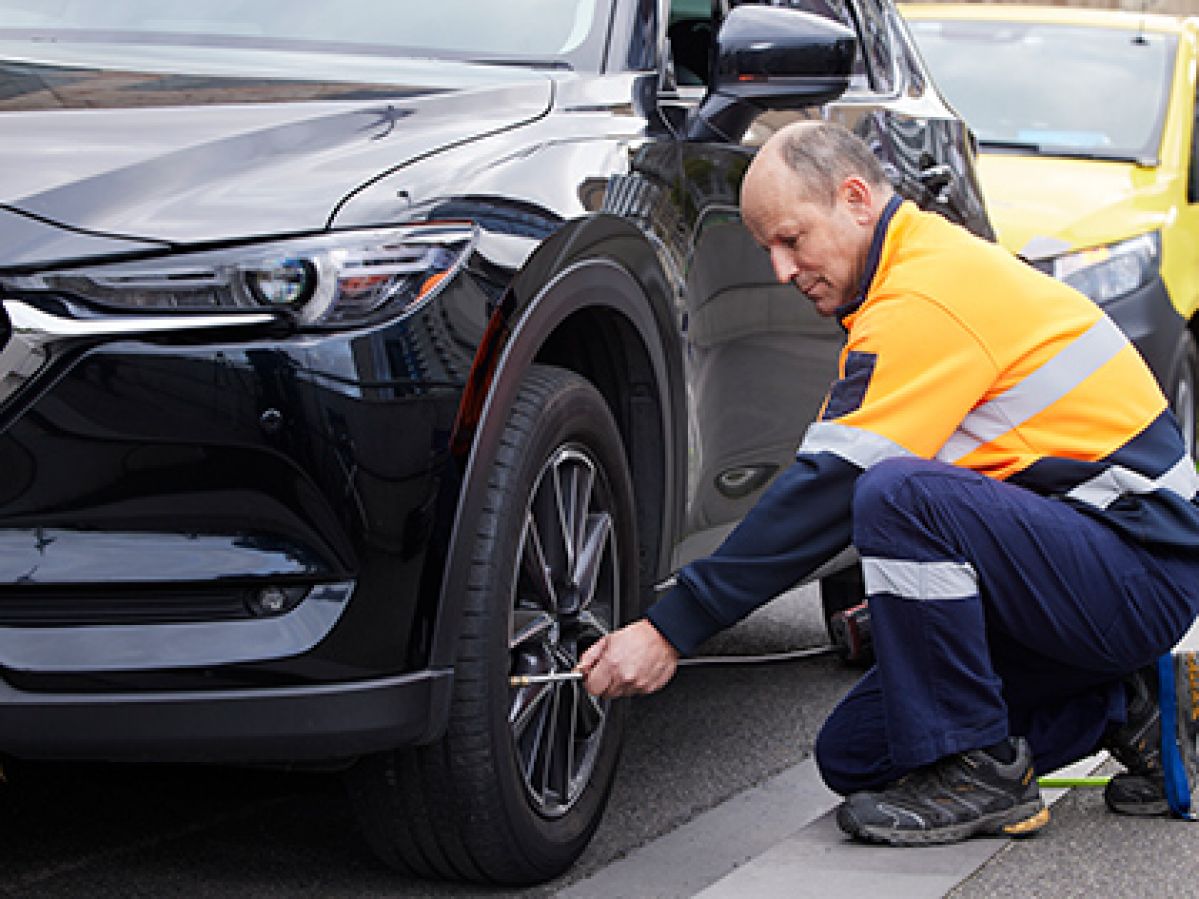 RACV Emergency Roadside Assistance patrolperson fixing a car's flat tire in Melbourne city.