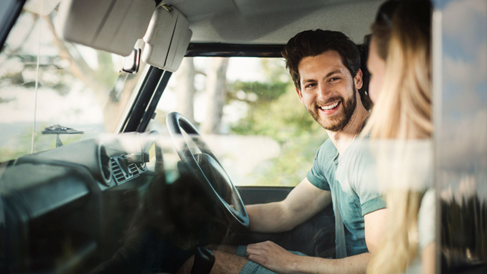 Smiling couple sitting in the front seats of a car.