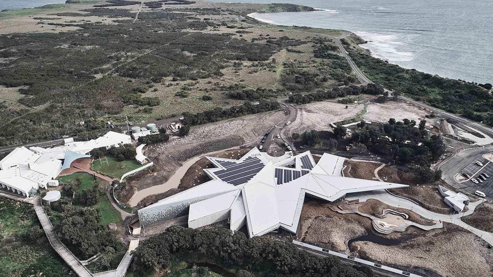 Aerial view of geometric building fitted with solar panels at Penguin Parade. 