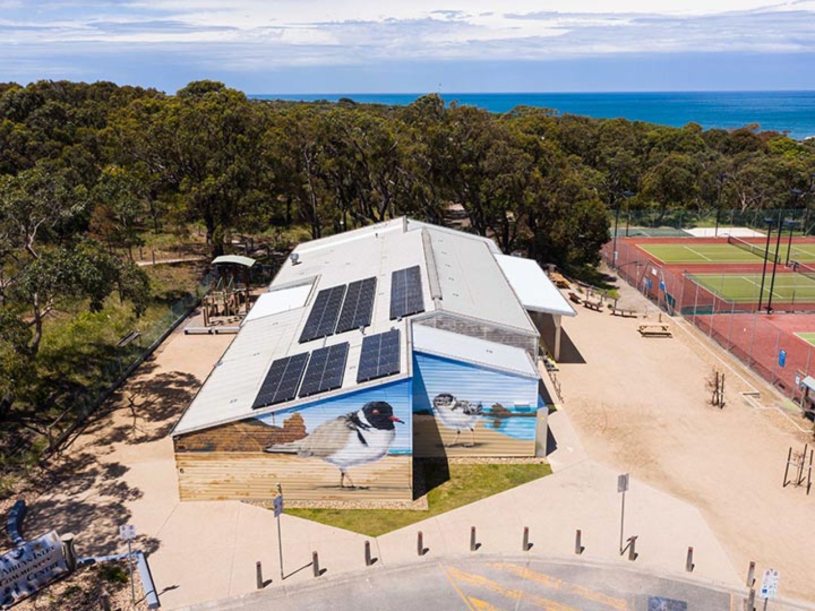 Aerial view of a community facility in Aireys Inlet, with a bird mural on the side and fitted with solar panels.