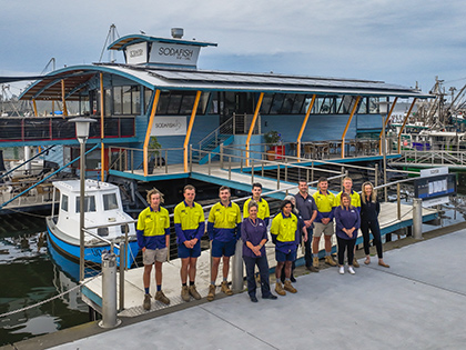 The RACV Solar team smiling in front of Sodafish restaurant, which has been fitted with solar panels.