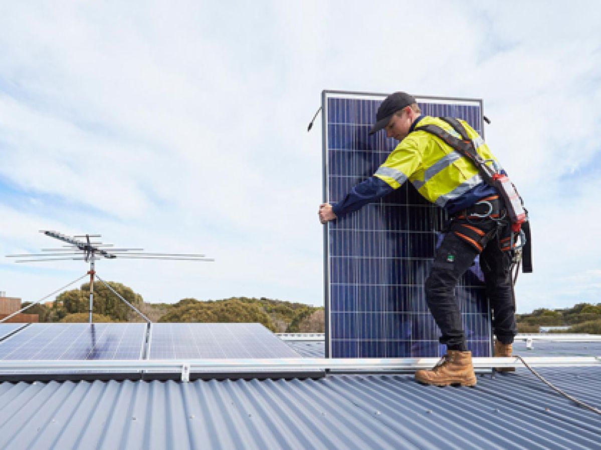 Tradesperson installing a solar panel on a property.