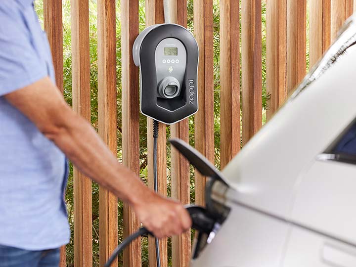Man plugging EV charger into electric vehicle