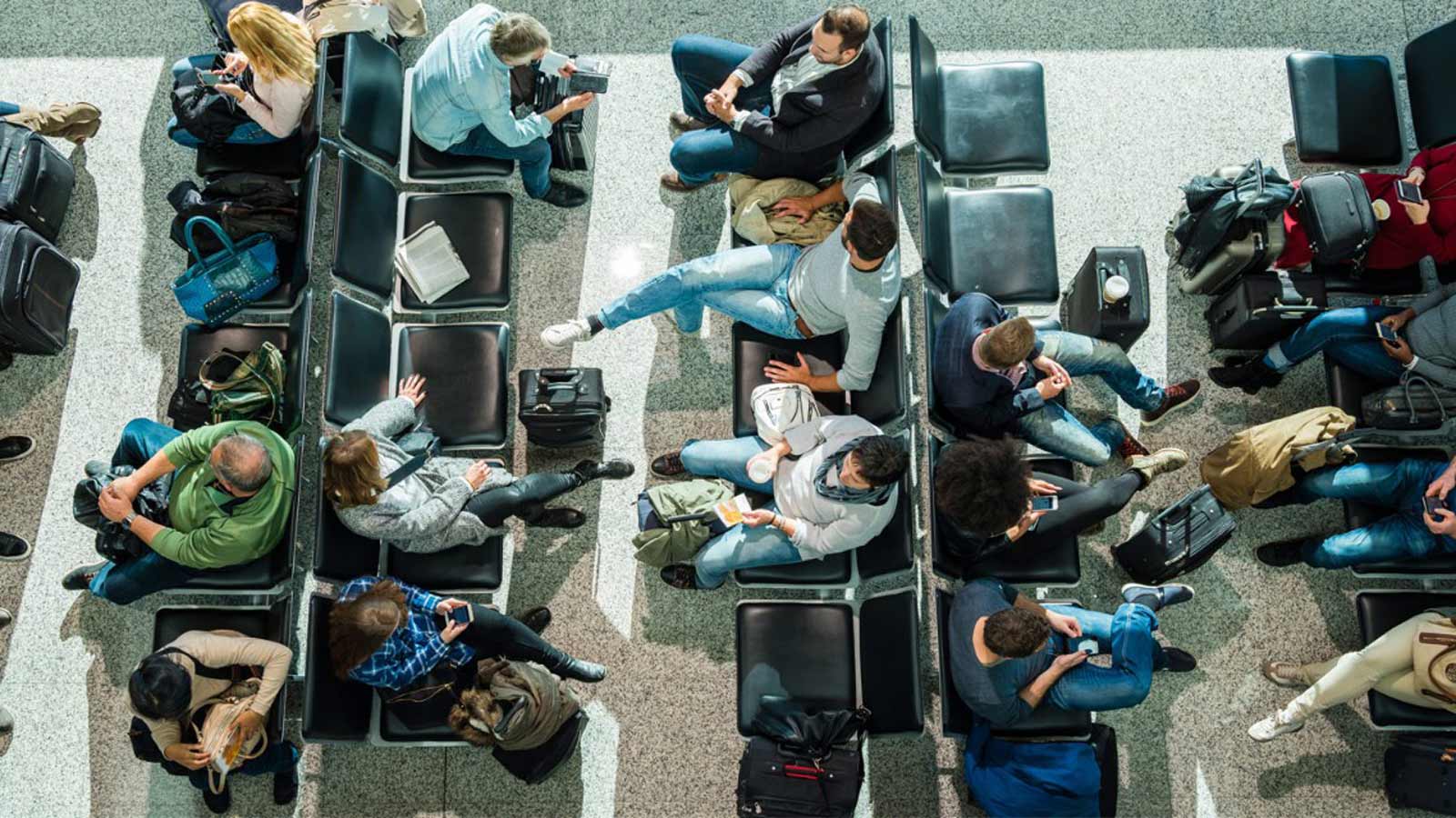 Aerial view of people waiting at an airport gate lounge. 