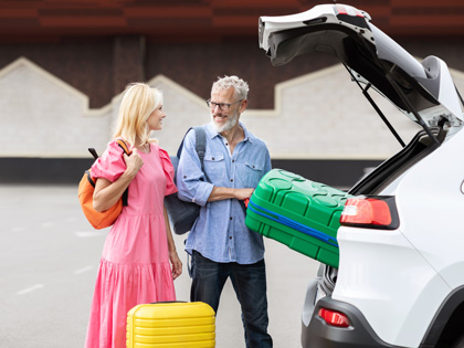 Couple getting their suitcases out of a car boot