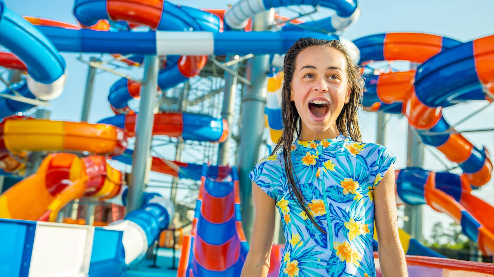 Young girl standing in front of colourful waterslides