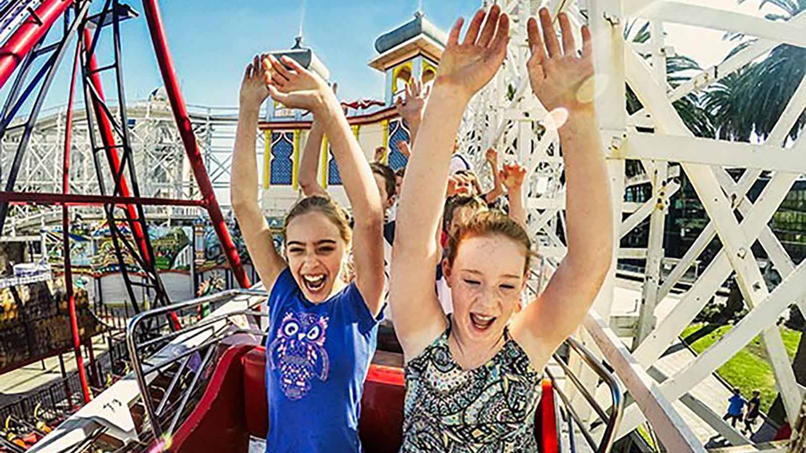 Children with hands up riding a rollercoaster at Luna Park in Melbourne.