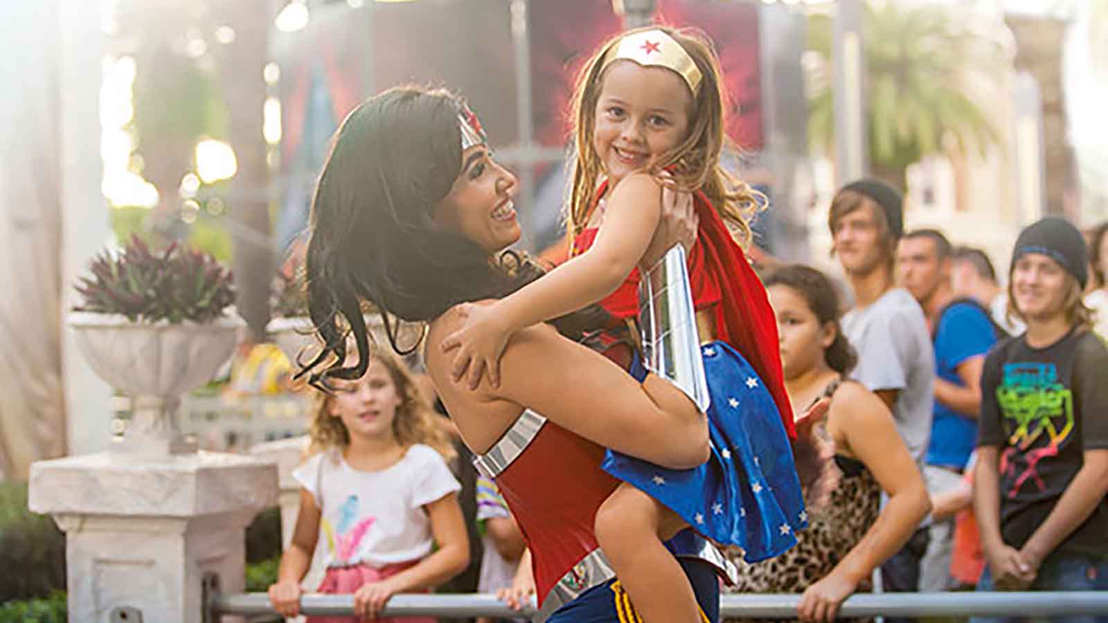 Small girl dressed as Wonder Woman hugging the Wonder Woman character actor at Movie World.