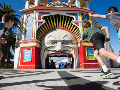 Three young kids running towards Luna Park in St Kilda