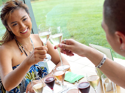 Couple smiling together and sitting at a table with glasses of wine.