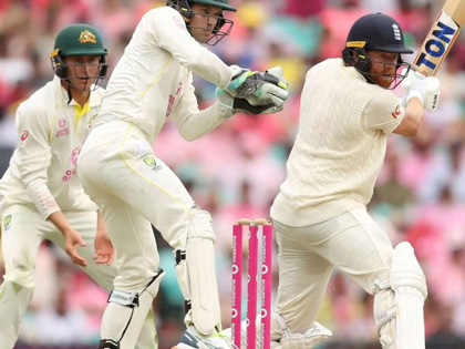 Three men playing cricket with a pink crowd in the background. 