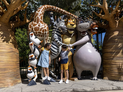 A couple of kids having a photo with the statues of the characters from Madagascar ar Dreamworld.