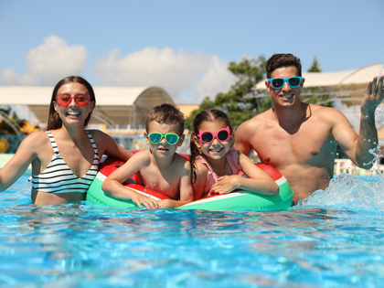 A group of four in a pool wearing colourful sunnies.