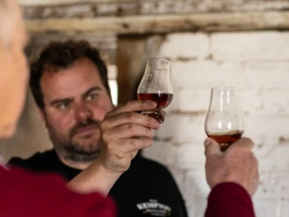 Two men holding up glasses of Whisky