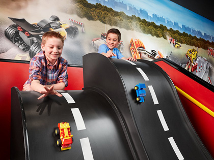 Two young boys racking lego cars down some slides. 