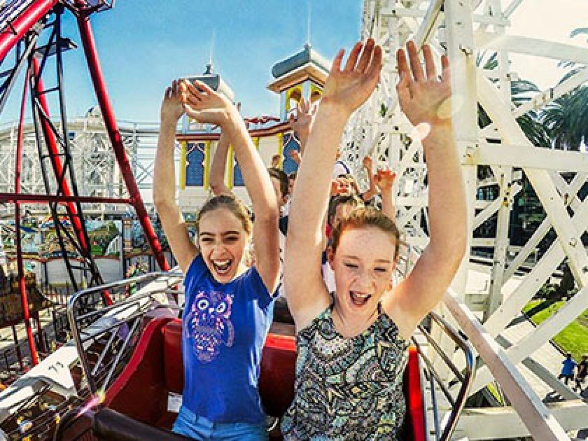 Children with hands up riding a rollercoaster at Luna Park in Melbourne.