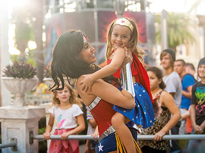Small girl dressed as Wonder Woman hugging the Wonder Woman character actor at Movie World.