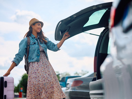 Woman getting her suitcase out of the car at the airport