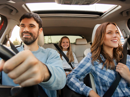 A young family smiling whilst in the car. 