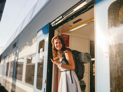 Woman looking out of the train wearing a hat and backpack