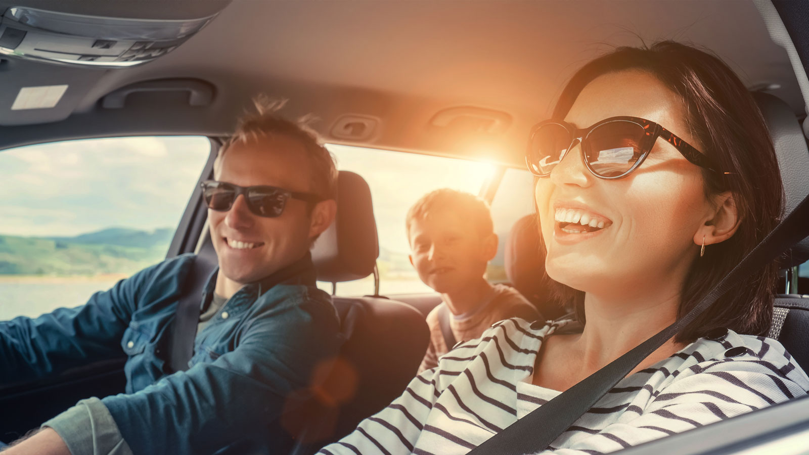 A young family in a car with the sun shining through the window. 