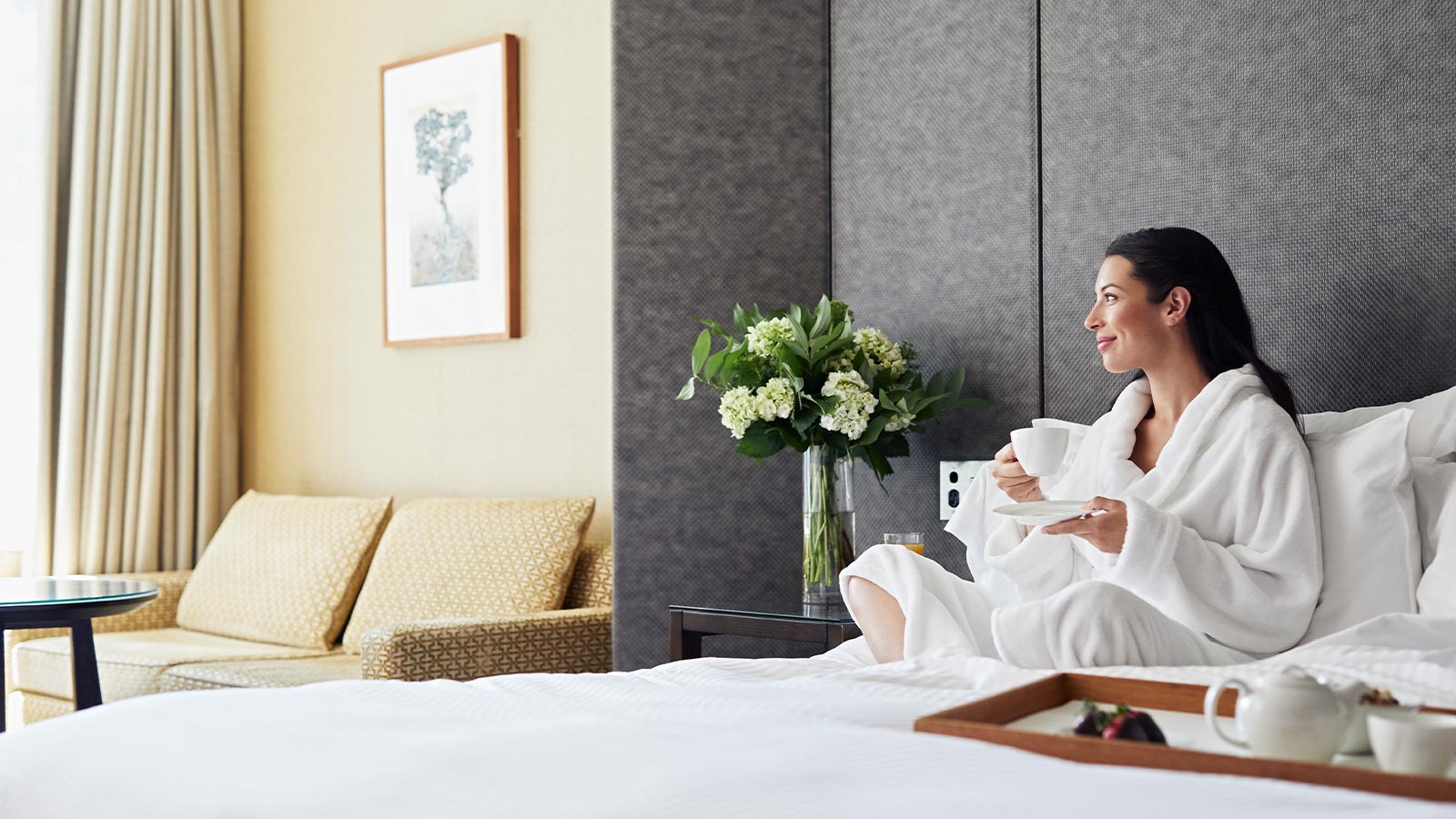 Member drinking tea in bed while staying at the city club.