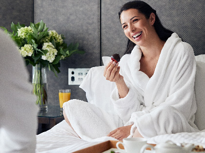 Woman eating strawberries in bed.