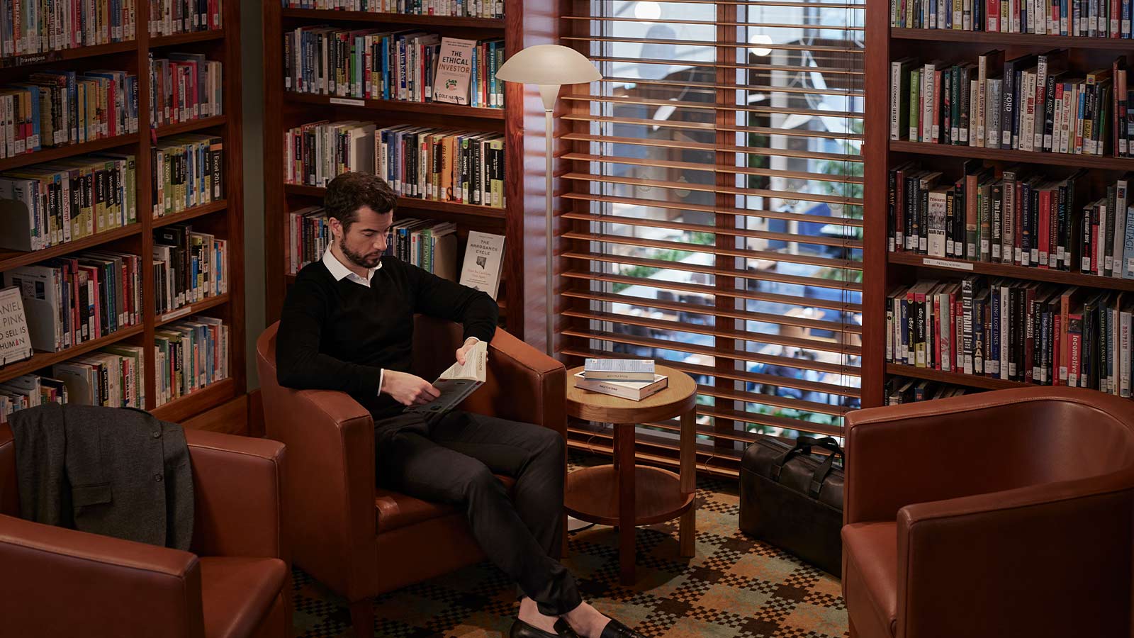 Member reading a book in the city club library.