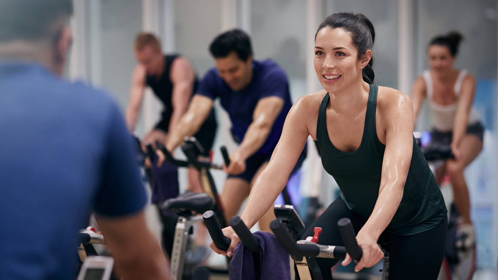 Woman riding an exercise bike in a group fitness class.