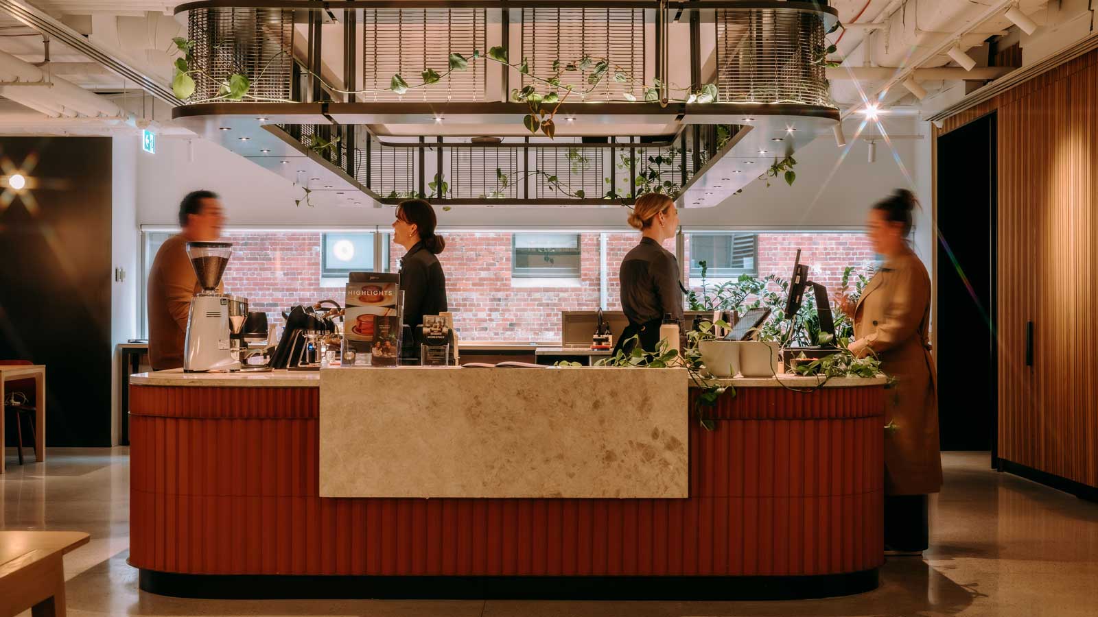 A staffed cafe with customers in a bright space with a big window. 