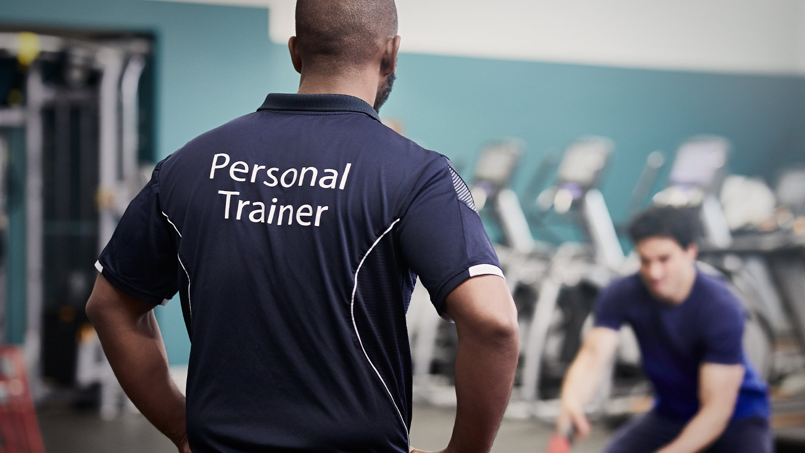 Personal trainer coaching a client in the gym.