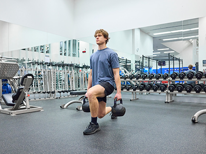Person lunging while holding kettlebells at RACV City Club's fitness centre.