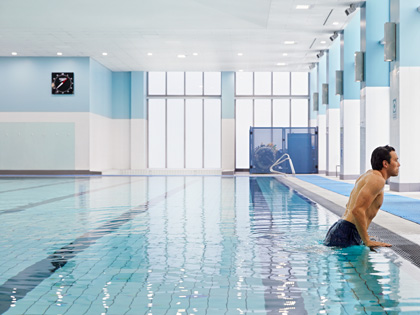 A man lifting himself out of the side of a swimming pool. 