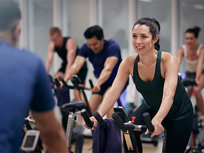 Woman riding an exercise bike in a group fitness class.