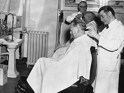 Barbers cutting clients hair in a vintage shot.