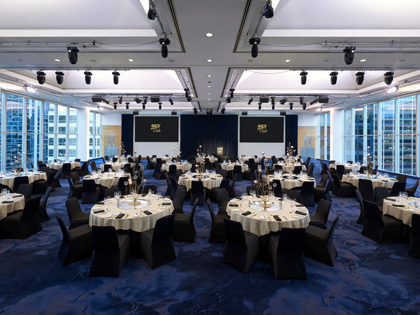 A confrerence room set up with round tables and double screens. 