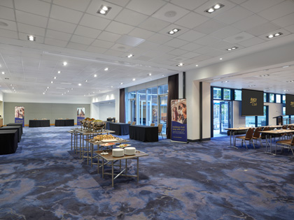 A conference room set up with with exhibition style tables and double screens. 