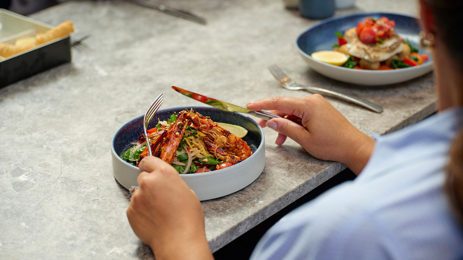 A man eating a prawn dish at RACV City Club's bistro.