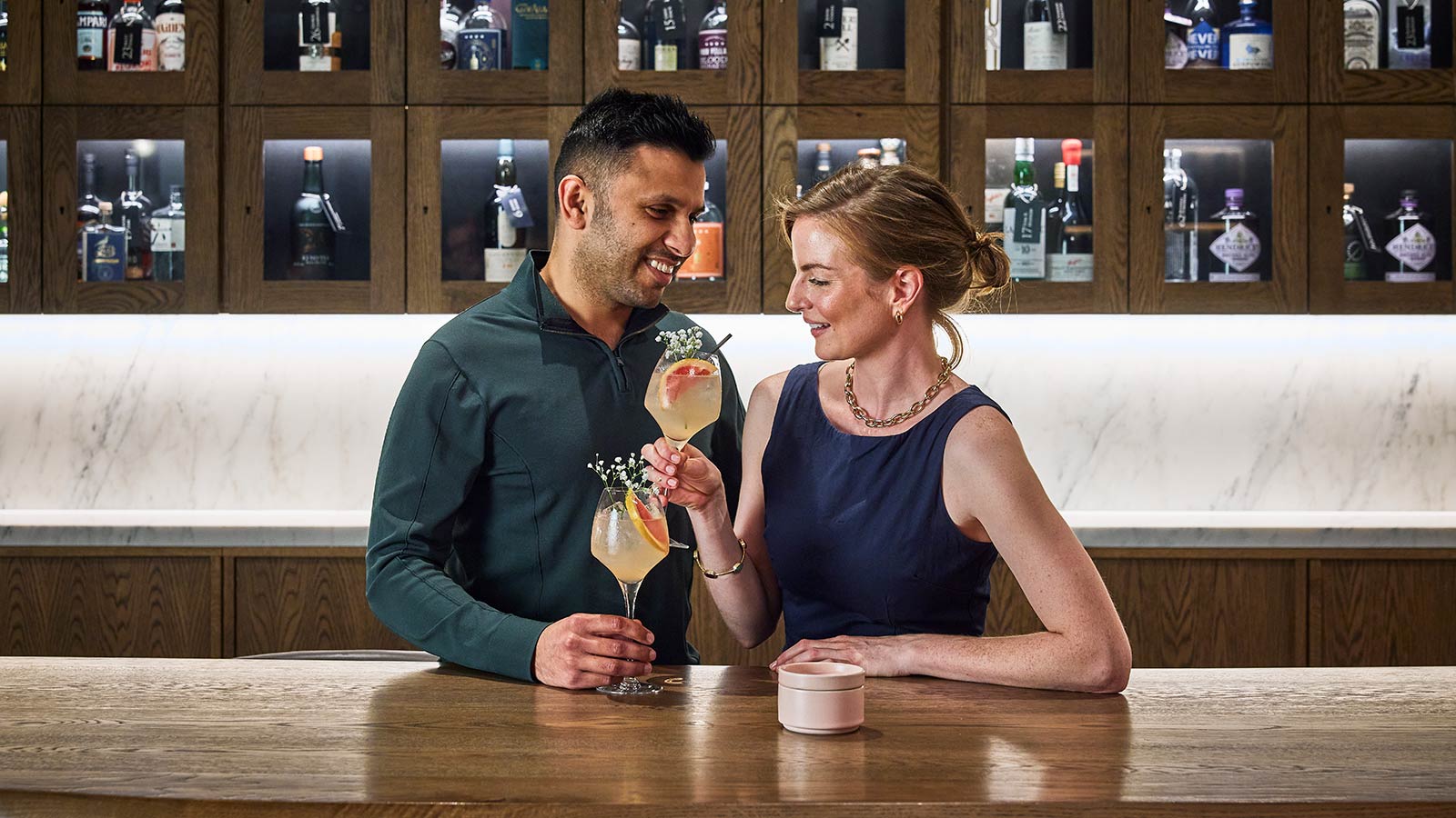 Couple smiling and toasting drinks at RACV City Club's wine bar.