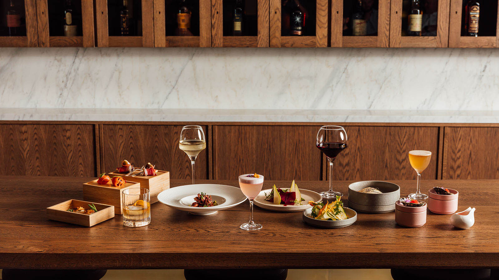 A selection of dishes and cocktails arranged on a wooden table at RACV City Club's Wine Bar.