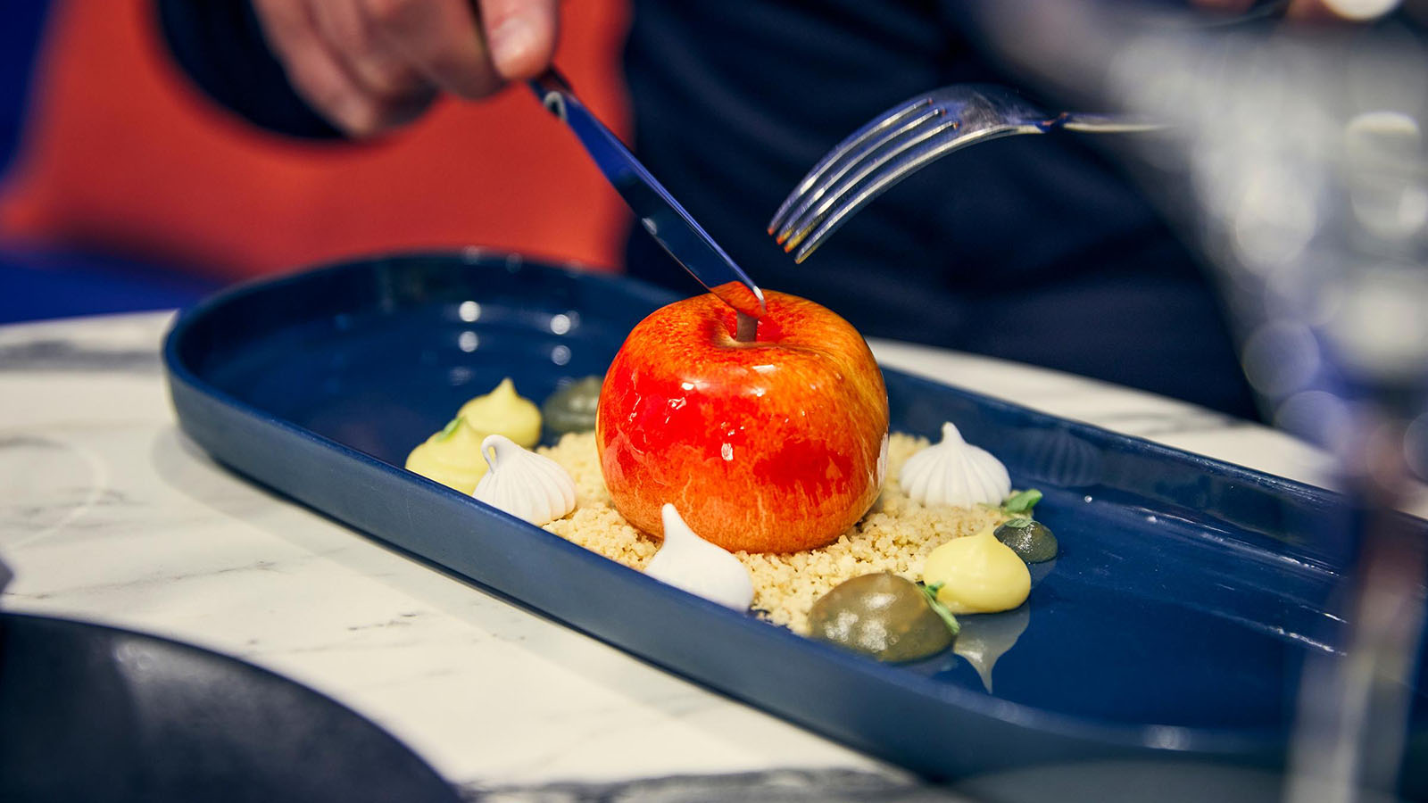 An apple dessert at Sojourn, with someone holding a knife and fork over the top, ready to tuck in.